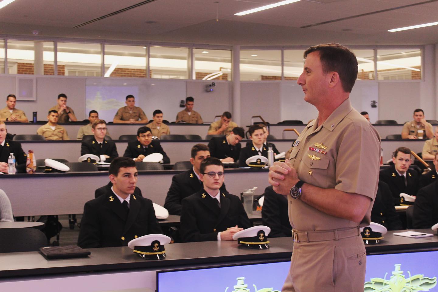 Naval Officer addresses a lecture hall of students in uniform