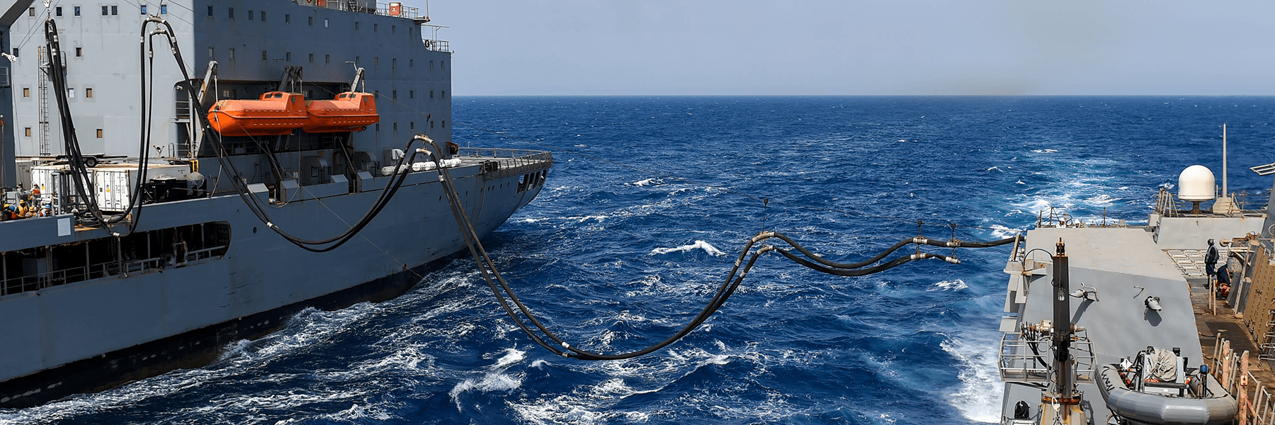 Supply ship fueling another ship while underway at sea